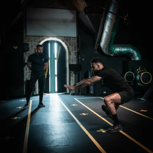 Patiënt oefent squat onder begeleiding tijdens sportfysiotherapie in Amsterdam Zuidoost