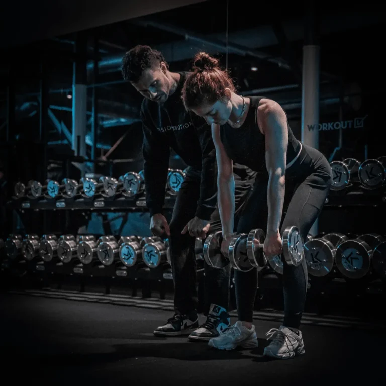 Trainer assisting woman with weights