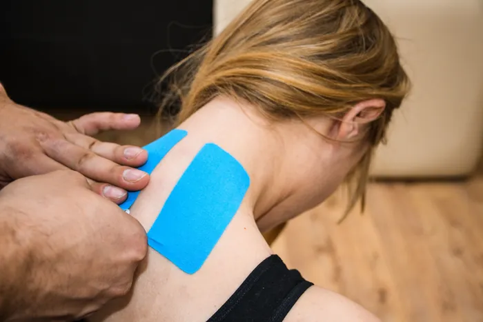 Fysiotherapeut van Fysio & Motion Diemen brengt medical tape aan bij nek van patiënt